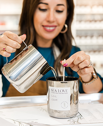 Happy customer pouring wax at Sea Love's DIY candle-making experience